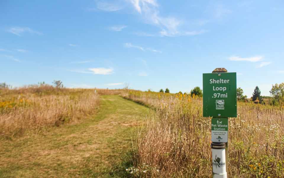 Sign by trail with meadow behind